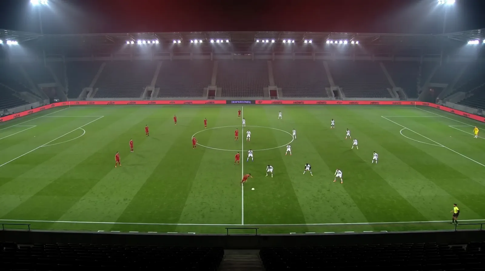 High tactical-camera view of an 11-a-side match in a floodlit stadium